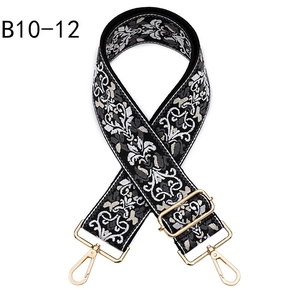 Detail of ethnic floral embroidery on black guitar style bag strap with gold metal hooks