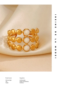 Close-up of 18K gold plated triple layered ring with white shell circular inlays on silk