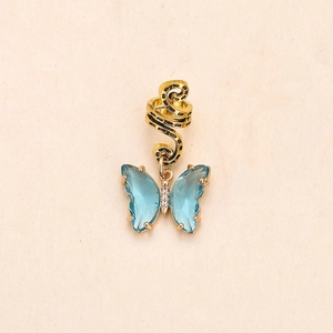 Detailed close-up of a gold-toned braid hair ring with a blue crystal butterfly pendant