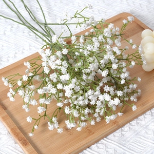 Close-up of artificial white gypsophila baby's breath on a wooden tray with soft lighting