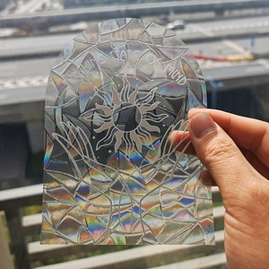 Close-up of holographic suncatcher sticker featuring sun design and palm hands