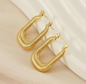 Detailed view of U-shaped gold earrings with horizontal textured finish and 18K plating