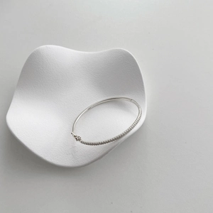 Detail of S925 sterling silver bracelet with pave diamonds on white ceramic tray