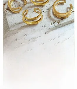 Detail of vintage gold-plated earrings with double-layered lines on travertine stone