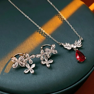 Detailed view of silver necklace and earrings with red pear-shaped zircon stones