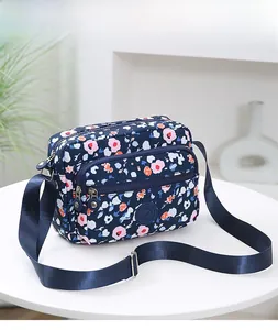 Close-up of navy floral crossbody bag with multiple zip pockets and adjustable strap