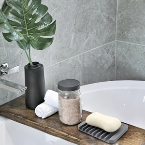 Detail view of gray silicone soap dish with a self-draining striped grate in a bathroom