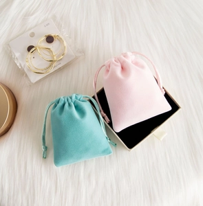 Pink and mint green plush velvet jewelry drawstring pouches on soft fur background