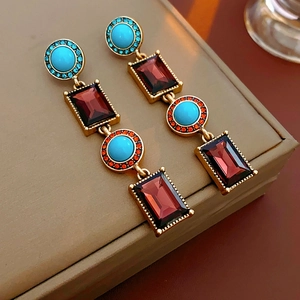 Detail of vintage gold earrings with ruby and turquoise stones and crystal fringe