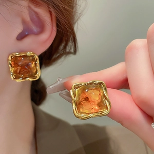 Detail of vintage square amber resin earrings with twisted golden metal frame