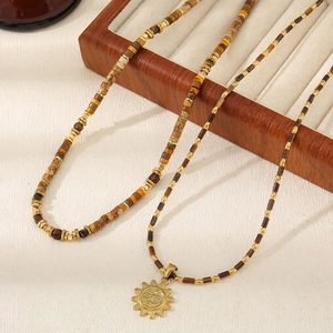 Ensemble collier en œil de tigre avec pendentif soleil doré sur plateau en bois