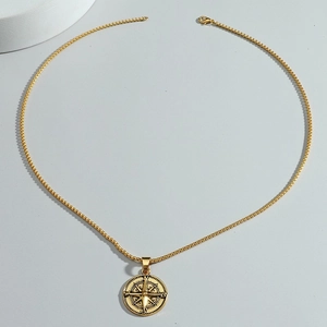 Detail of a gold compass pendant featuring crystal accents on a fine box chain