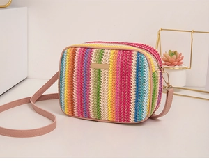 Detail of colorful rainbow striped woven camera bag with pink faux leather strap