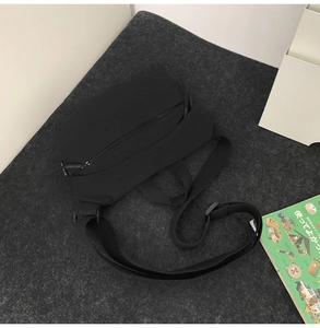 Detailed top view of a minimalist black nylon chest bag with adjustable shoulder strap