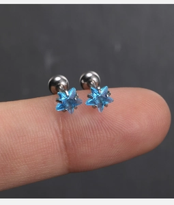 Vue macro de boucles d'oreilles étoile avec pierre bleue sur le bout d'un doigt