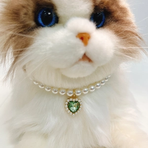 Elegant pet pearl necklace with a green heart crystal pendant on a cat model