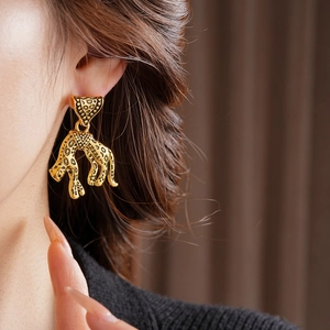 Close-up of vintage leopard earrings in antique gold finish with black spotted details