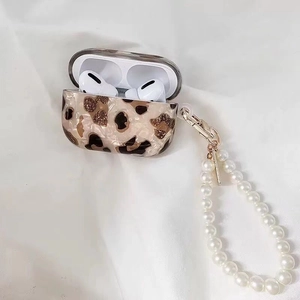 Détail d'étui AirPods Pro motif léopard ambré avec dragonne en perles et boucle dorée