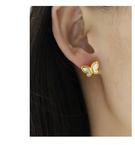 Detail of 18k gold butterfly stud earring with shimmering white shell inlay on model