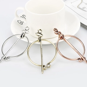 Three Viking metal brooches in silver, gold, and rose gold on a clean white desk