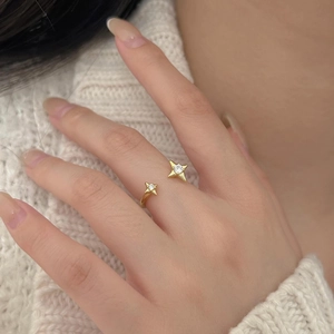 Detailed close-up of golden star ring with white zircon on a soft knit background