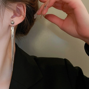 Close-up of elegant long silver tassel earrings worn by a model in a black suit