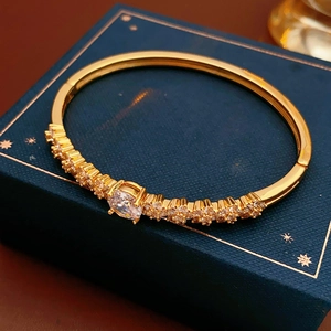 Close-up of gold plated flower bracelet featuring zircon stones on a navy gift box