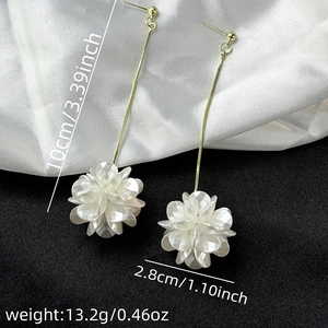 Detail view of long tassel earrings with dimensions: 10cm length and 2.8cm shell flower