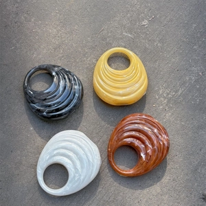 Close-up of four acrylic handbag handles in marble, amber, pearl, and tortoiseshell patterns