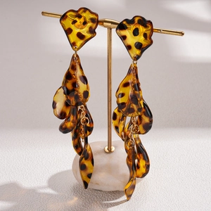 Macro detail of acrylic leopard print petal tassel earrings on a display stand