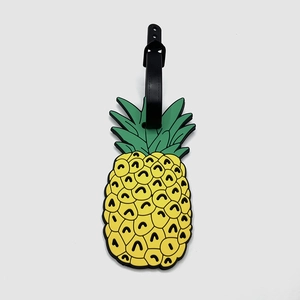 Close-up of yellow pineapple shaped PVC luggage tag with green leaves and black strap