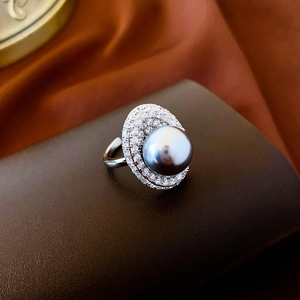 Macro shot of silver pearl ring with dark grey pearl and white zircon inlay on leather base
