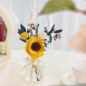 Close-up of reed diffuser with yellow sunflower and dried flower bouquet in glass bottle