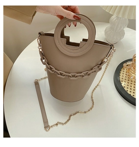 Detail showing the khaki PU leather handbag with circular handle and chain accessory