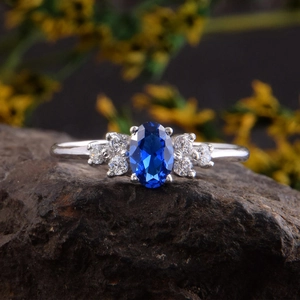 Macro-opname van een ring met ovale blauwe edelsteen en zij-diamanten op een steen