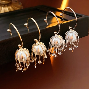 Détail de boucles d'oreilles cage à perles avec glands étoiles en finitions or et argent