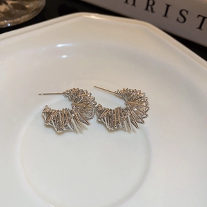 Detail of silver U-shaped layered coil earrings on a white ceramic plate