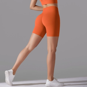 Detail view of high-waisted orange compression shorts with side pockets and lifting effect