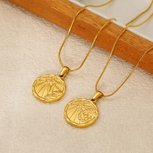 Detail of gold snake chain necklaces with engraved sun coin pendants on a wood tray