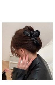 Dettaglio dell'elegante molletta per capelli in raso nero con fiocco su capelli castani