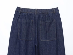 Detail view of dark blue denim wide leg pants with elastic waist and rear patch pockets