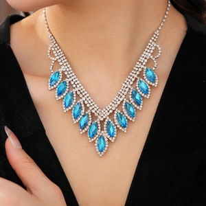 Detail of blue teardrop gemstone necklace set on model wearing a black V-neck top