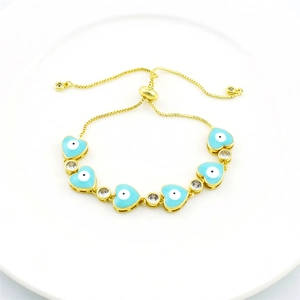 Detail of adjustable gold bracelet with blue heart evil eye charms and zircons