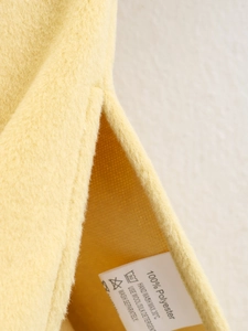 Close-up of yellow wool-like fabric texture with clothing care label for quality detail