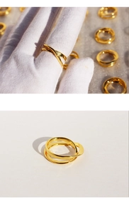 Detailed view of layered irregular cross gold rings on hand with professional studio lighting