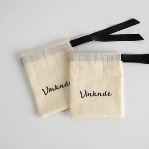 Detail of off-white cotton linen drawstring gift bags with black silk ribbon ties