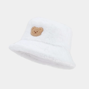 Detail of soft white plush bucket hat featuring a brown bear embroidery patch