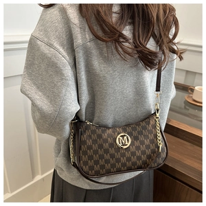 Model wearing a vintage brown crescent bag with M-pattern and gold chain strap