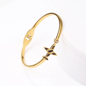 Bracelet avion en acier inoxydable plaqué or 18k avec zircon sur un support minimaliste