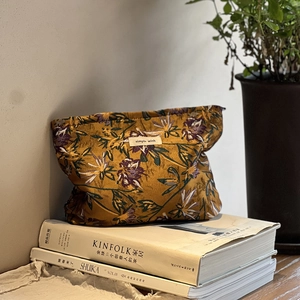 Caramel floral jacquard toiletry bag with simple wish label on a stack of magazines